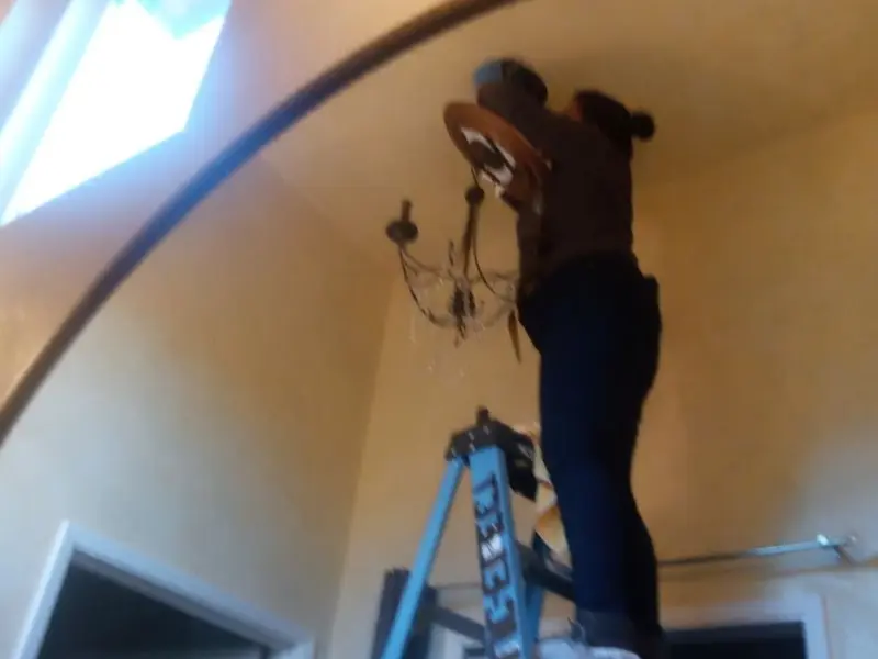 Electrician installing a chandelier in a Dunlap residence